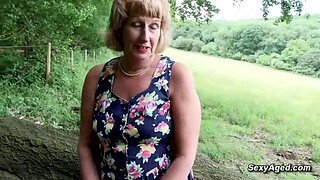 British blonde amateur solo granny Rosemary in colorful summer dress sitting on a tree trunk and playing with her shaved pussy outdoor